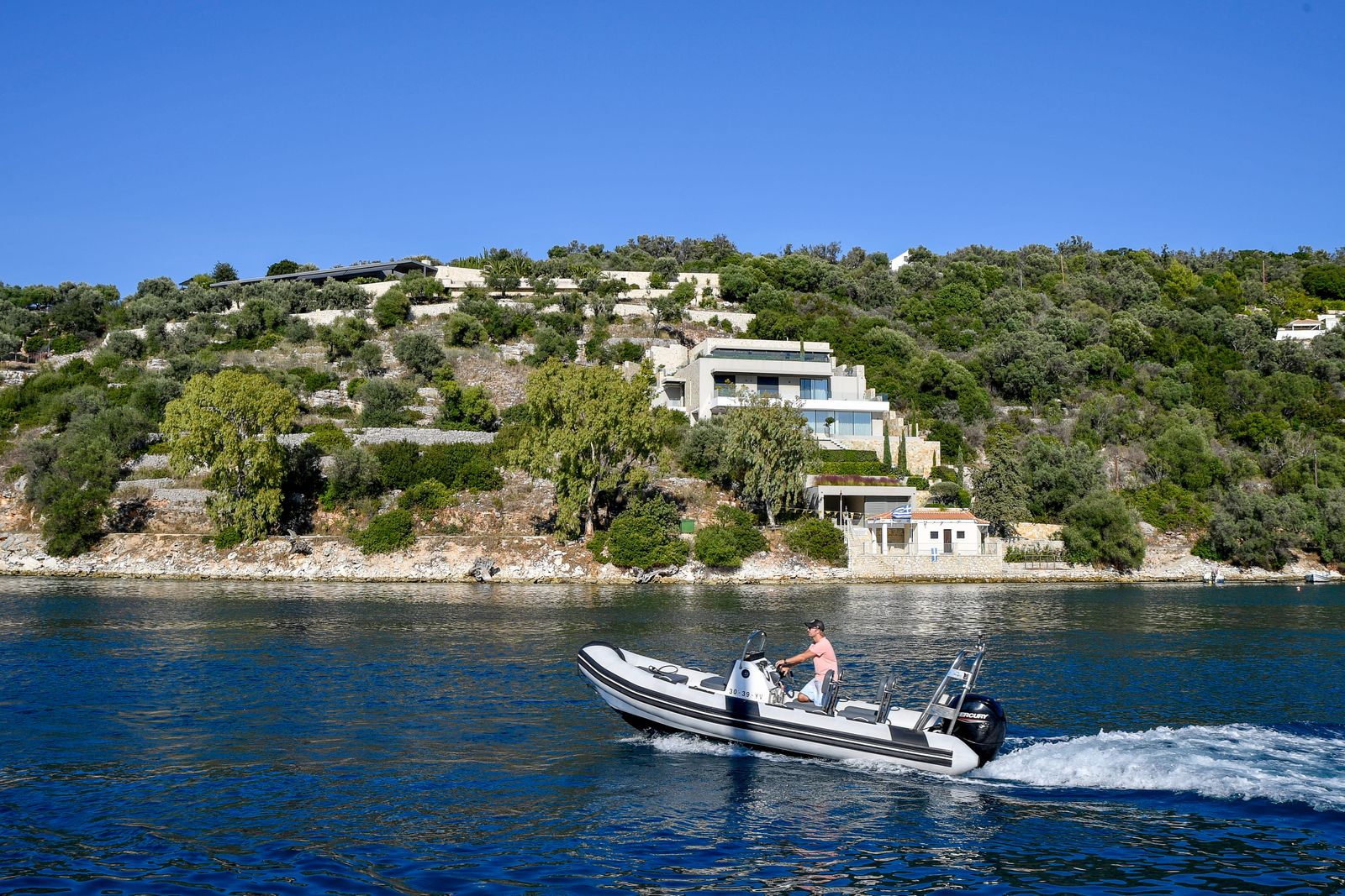 Speedboat cruising a scenic Greek coastline from a resort area